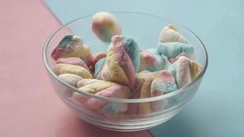 Marshmallow candy in a bowl on blue . video