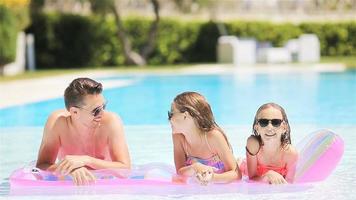 Happy family of four in outdoors swimming pool video