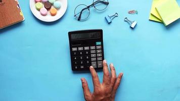 Top view of man hand using calculator on blue background . video