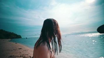 a ásia mulher com molhado Loiras cabelo é sentado em a de praia enquanto desfrutando a Visão do a azul mar video