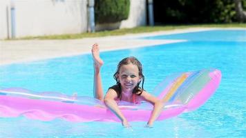 adorable fille avec matelas gonflable dans la piscine extérieure video