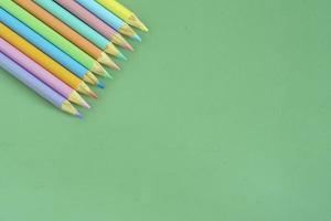 Pastel colored pencils, top view on green background, illustration concept, education and back to school photo