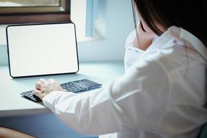 The new normal. A businesswoman is using  computer and phone to work for a company. over the Internet on your desk at home. photo