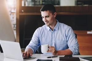 los gerentes de marketing masculinos toman café mientras trabajan para reducir la somnolencia antes de usar computadoras, ipads y documentos de análisis de marketing. foto