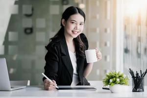 Female marketing managers drink coffee while working to reduce drowsiness before using tablet computer, and marketing analysis papers. photo