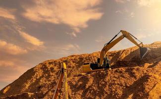 Backhoe working on huge sawdust pile in paper production factory. Bucket of digger digging wood chips. Pile of wood chips from pulp mill against the sky. Pulp and paper industry. Bulldozer  working. photo