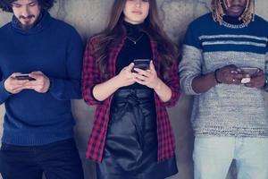 casual multiethnic business team using mobile phones in front of a concrete wall photo