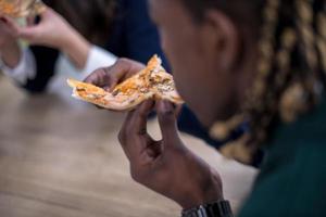 equipo de negocios multiétnico comiendo pizza foto