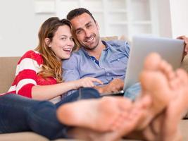 relaxed young couple working on laptop computer at home photo