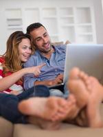 relaxed young couple working on laptop computer at home photo