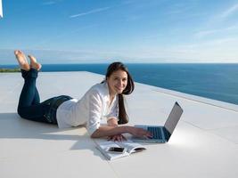 relaxed young woman at home working on laptop photo