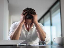 frustrated young business man working on laptop computer at home photo