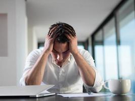 frustrated young business man working on laptop computer at home photo