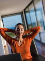 relaxed young woman at home working on laptop computer photo