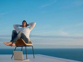 relaxed young man at home on balcony photo