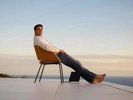 relaxed young man at home on balcony photo