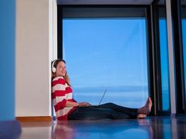 relaxed young woman at home working on laptop photo