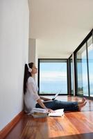 relaxed young woman at home working on laptop photo