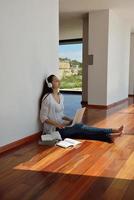 relaxed young woman at home working on laptop photo