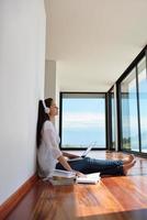 relaxed young woman at home working on laptop photo