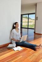 relaxed young woman at home working on laptop photo