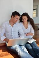 relaxed young couple working on laptop computer at home photo