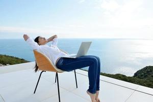 relaxed young woman at home working on laptop photo