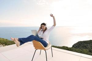 relaxed young woman at home working on laptop photo