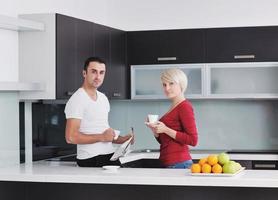 Happy couple reading the newspaper in the kitchen at breakfast photo