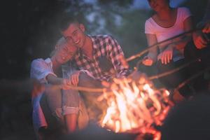 young friends relaxing around campfire photo