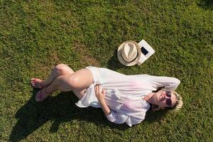 parte superior ver desde encima de un mujer acostado y relajante en un prado cubierto con verde césped en un soleado verano o primavera día. foto