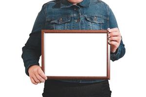 A blank diploma or a mockup certificate in the hand of a woman employee wearing a denim shirt on white background with a clipping path. The The horizontal picture frame is empty and the copy space. photo