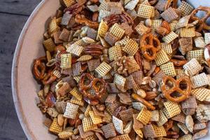 Holiday party mix of nuts, grain cereals, and pretzels in large bowl flat lay photo