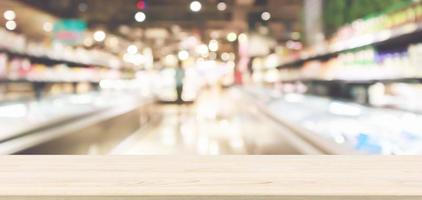 Wood table top with Abstract supermarket grocery store refrigerator blurred defocused background with bokeh light photo