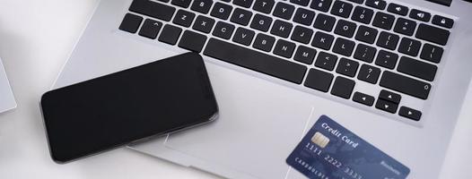 Office online paying, stay home shopping, electronic payment with credit card concept, laptop on white table background with shop cart, close up. photo