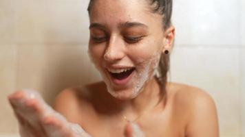 jeune femme dans un bain moussant rit et tapote des bulles sur le visage video