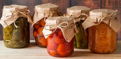 Pickled farm vegetables in glass jars on wooden background. Fermented trending food. Home rustic style. photo