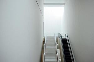 nuevo moderno escalera mecánica y escaleras en mínimo blanco edificio interior foto