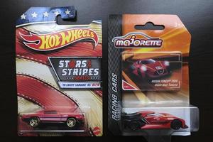 A Hot Wheels Chevy Camaro die cast toy car and a Majorette Nissan Concept 2020 Vision Gran Turismo diecast toy car on a table. photo