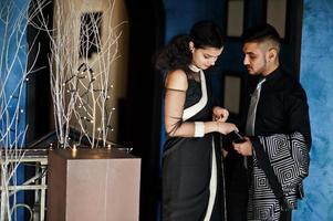 encantadora pareja india enamorada, vestida con sari y traje elegante, posada en el restaurante. foto