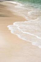 cerca arriba olas textura lapeado a través de intacto arena apuntalar soleado verano. foto