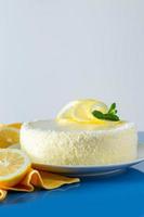 Lemon cake with coconut flakes on blue background. Delicate dessert with cream. photo