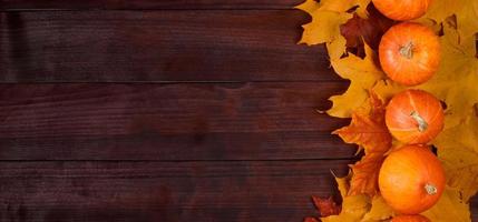 Autumn harvest. Ripe pumpkins and fallen leaves on wooden background. Thanksgiving and halloween concept. photo