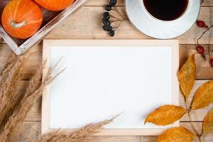 Autumn flat lay. Cup of hot espresso coffee and fallen yellow leaves on wooden background. Empty frame mock up for text. Morning concept.