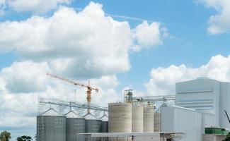 Animal feed factory construction site. Agricultural silo at feed mill factory. Tank for store grain in feed manufacturing. Seed stock tower for commercial animal feed production. Animal food industry. photo