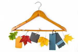 Autumn sale and discount. Clothes hanger, yellow leaves and blank labels on white background. Concept for advertising. photo