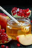 Traditional Jewish religious holiday Rosh Hashanah. Apples, pomegranates and honey on dark wooden background. Vertical photo. photo