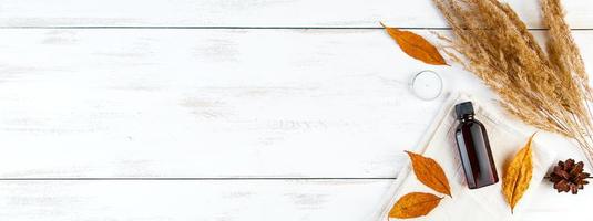 Autumn skin care concept. Bottle of pine essential oil on a white wooden background. Aromatherapy and eco-friendly cosmetics. photo