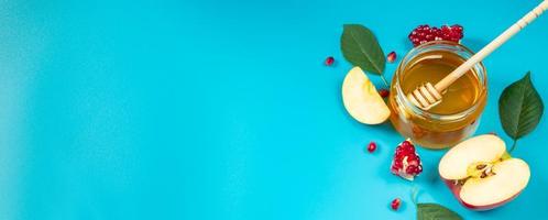 Apples, honey and pomegranates on blue background. Happy Rosh Hashanah. Jewish religious holiday concept. Banner format. photo