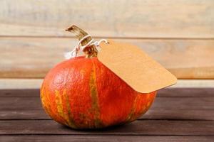 Harvest and autumn sale concept. Ripe pumpkin with  label on a wooden background. Thanksgiving holiday. Copy space. photo